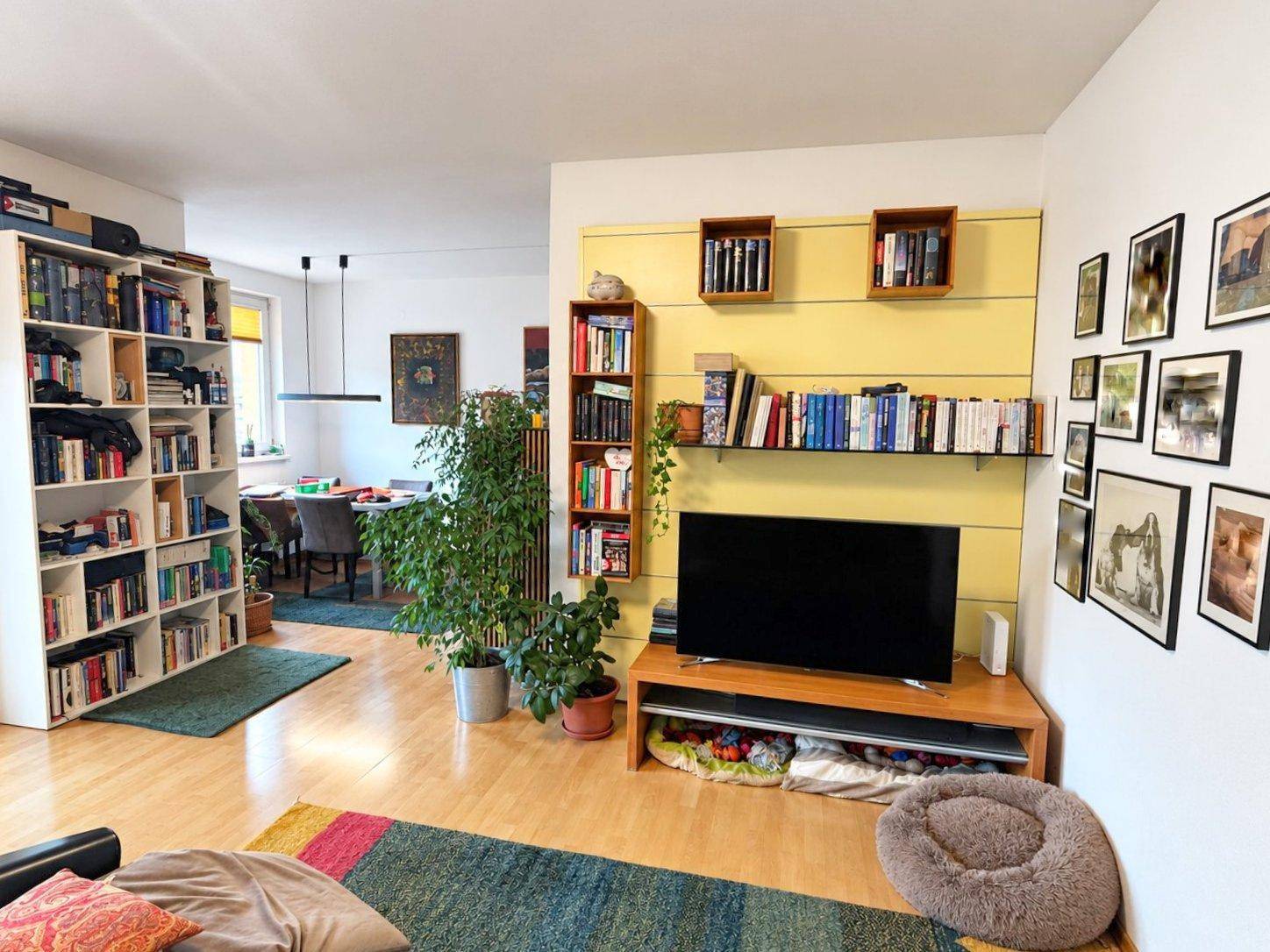 Geräumiges Wohnzimmer mit TV, Bücherregalen und offenem Übergang zum Essbereich.