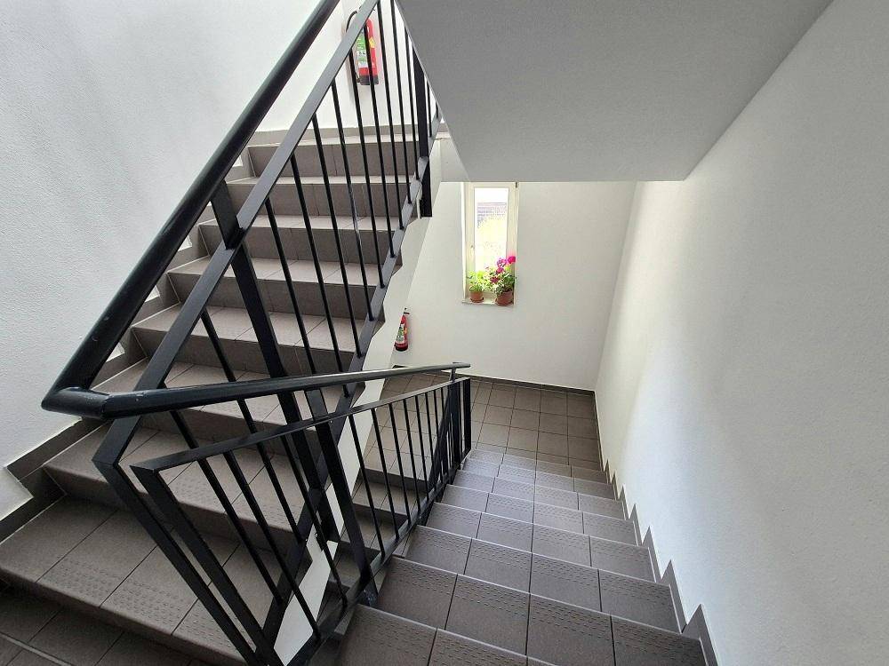 Treppenhaus mit gefliesten Stufen und Geländer, das die verschiedenen Etagen verbindet.