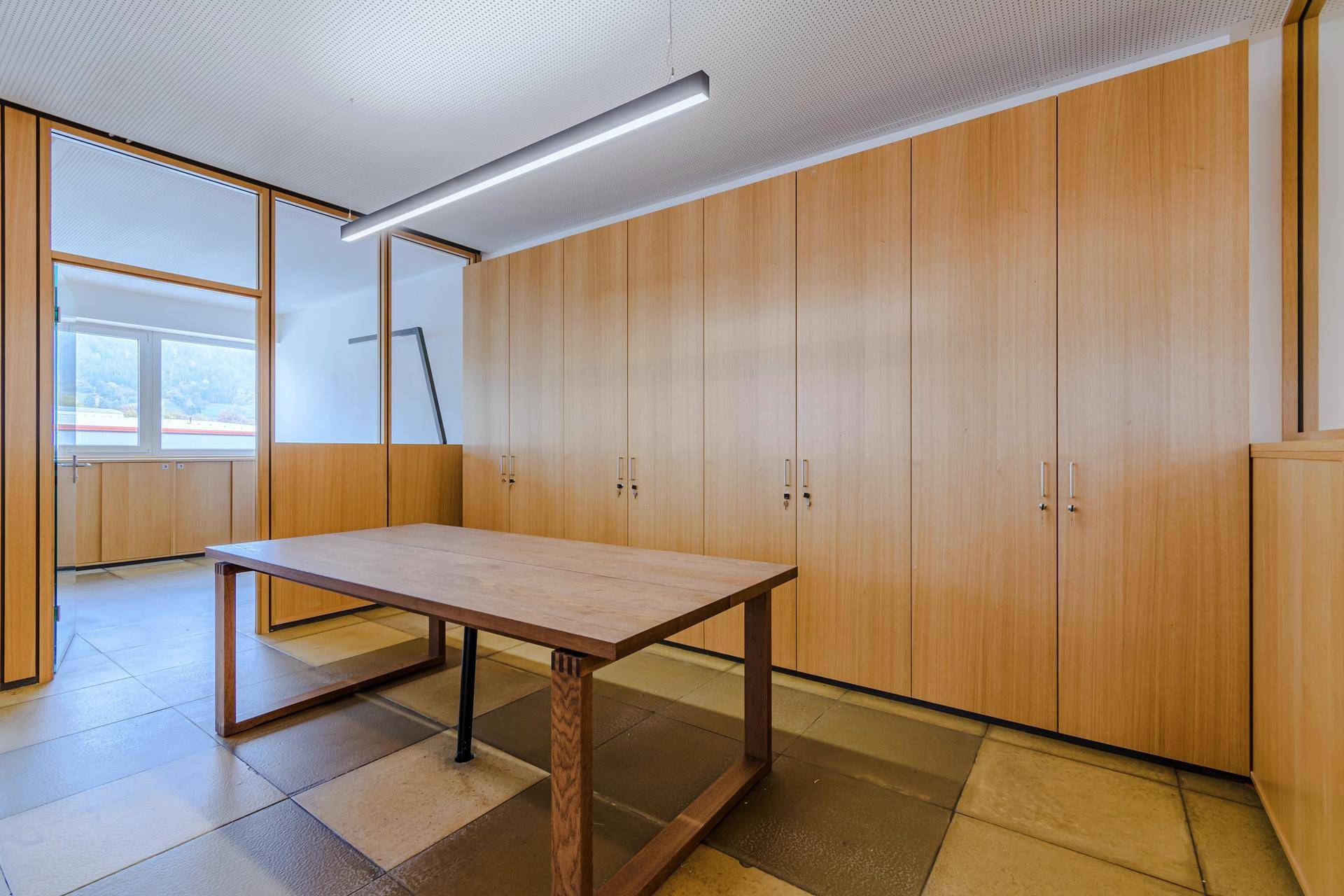 Großer Besprechungsraum mit Holztisch und umfangreichen Einbauschränken entlang der Wand.