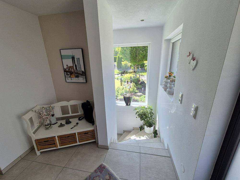 Heller Flur mit Fenster und Blick in den Garten, der zur Treppe ins Untergeschoss führt.