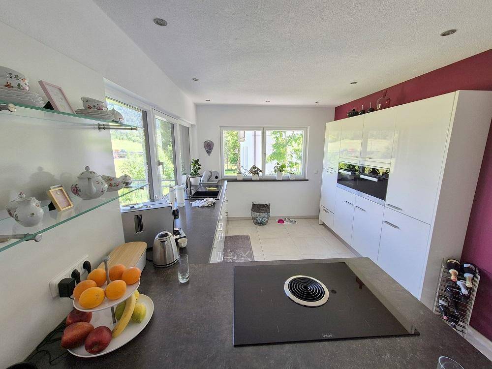 Moderne Küche mit weißen Hochglanzfronten, dunkler Arbeitsplatte und Induktionskochfeld.
