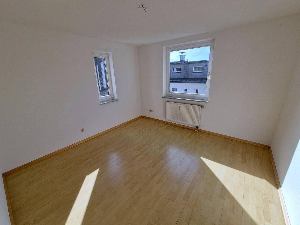 Geräumiges Schlafzimmer mit Laminatboden und zwei Fenstern für gute Belichtung.