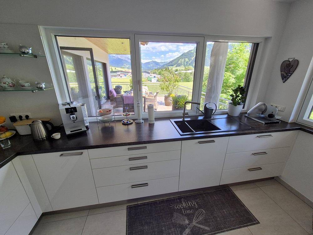 Helle Küche mit großen Fenstern, die einen weiten Blick auf die Berge und die Terrasse bieten.