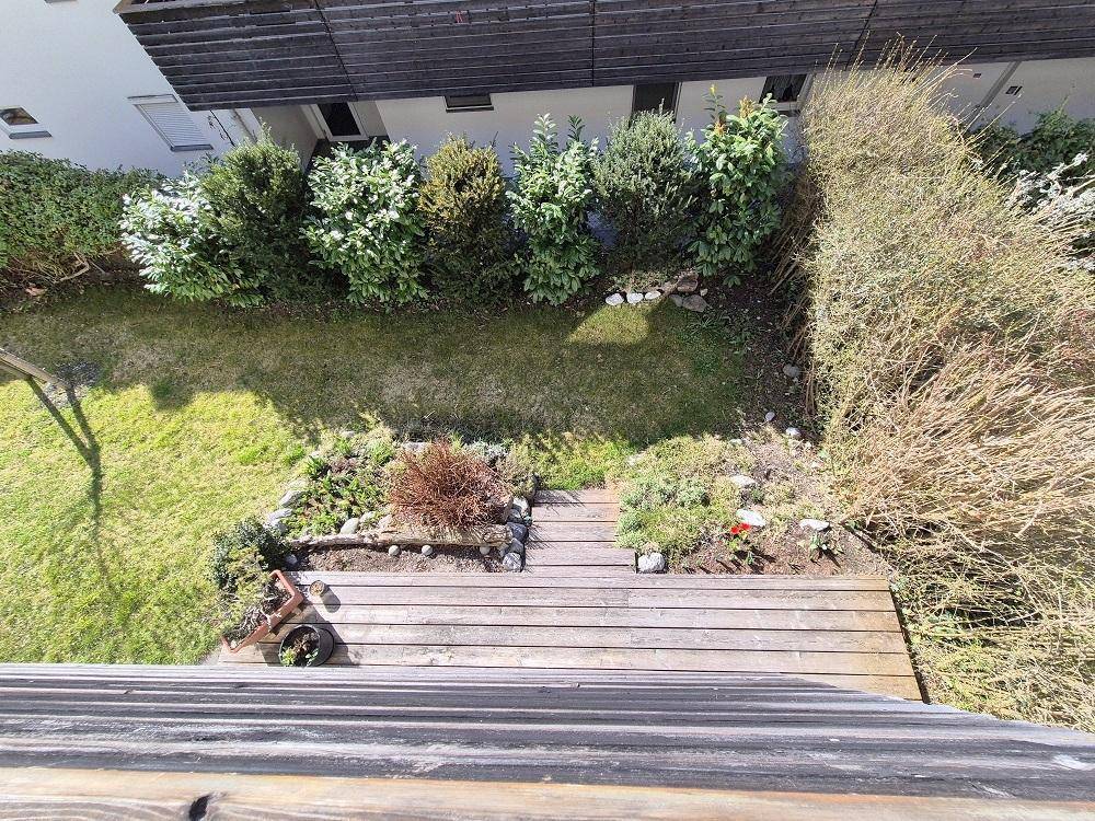 Blick von oben auf den gepflegten Gartenbereich mit Rasenfläche und Bepflanzung.