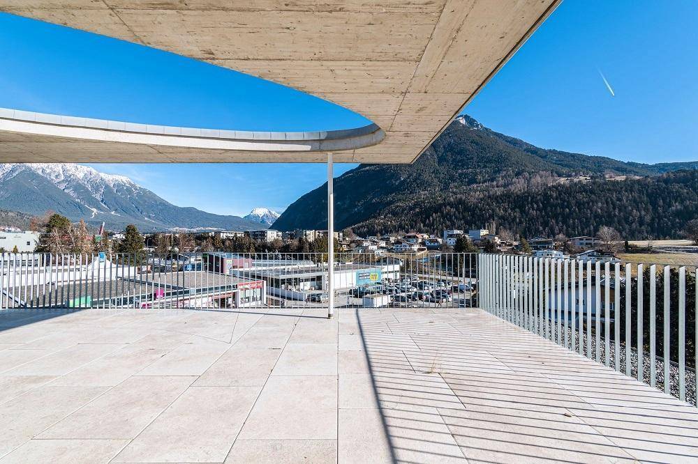 Großzügige Dachterrasse mit Fliesenboden und beeindruckendem Panoramablick auf die Berge.