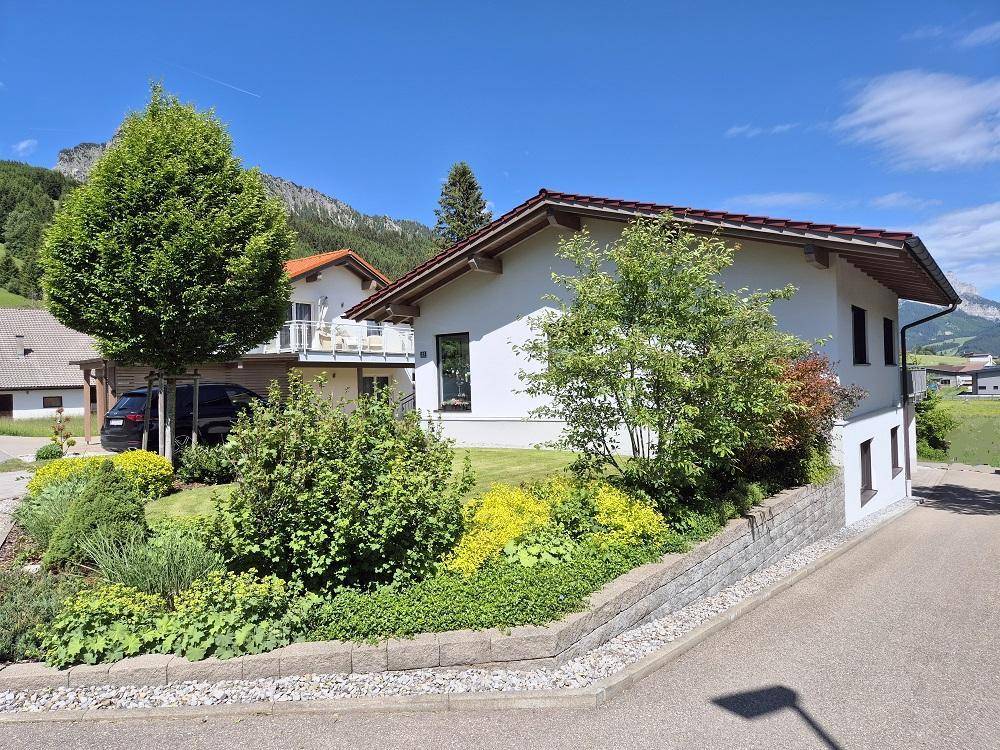 Seitlicher Blick auf das Haus mit terrassiertem Gartenbereich und üppiger Bepflanzung.