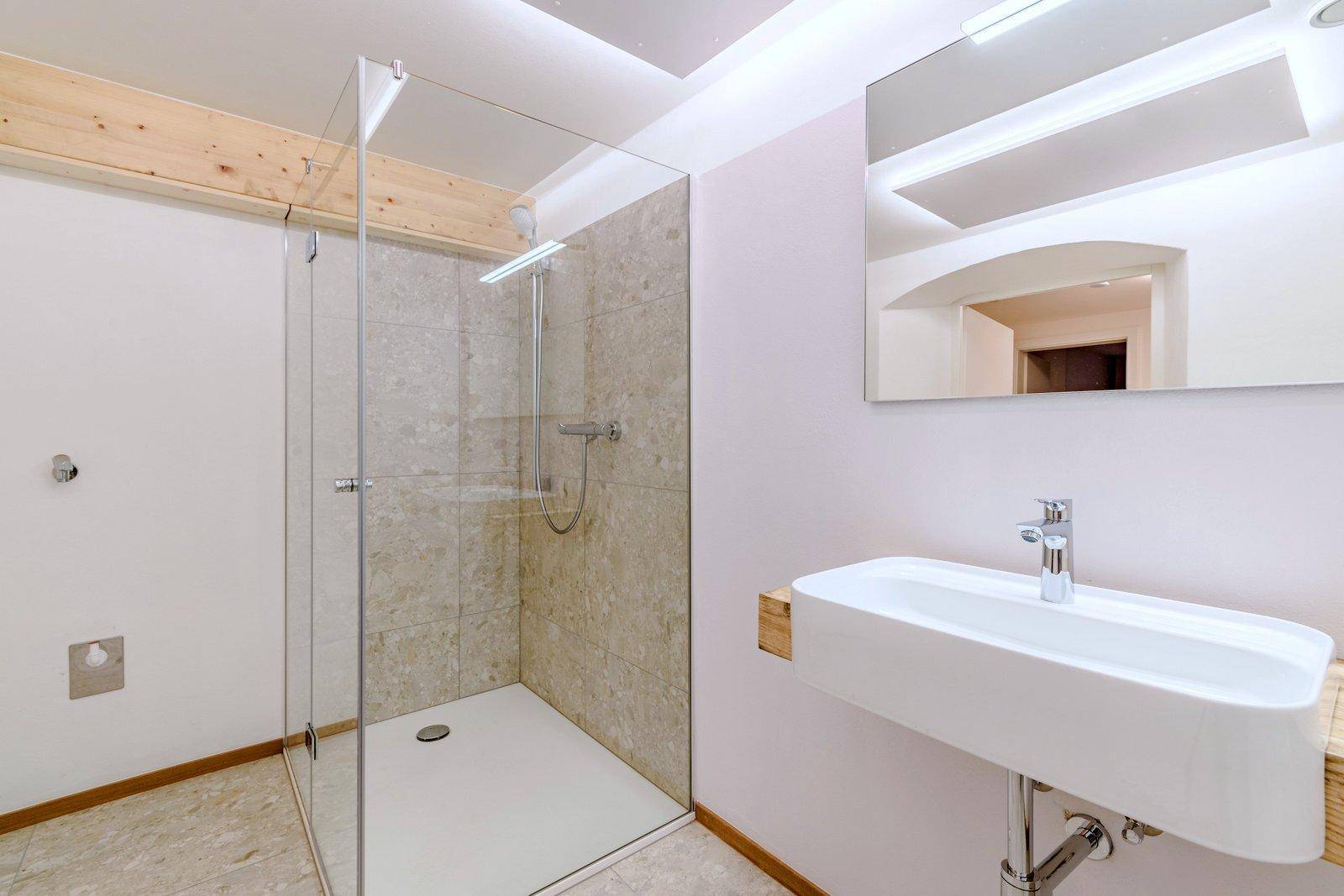 Modernes Badezimmer mit begehbarer Dusche, Fliesen und einem schwebenden Waschtisch.