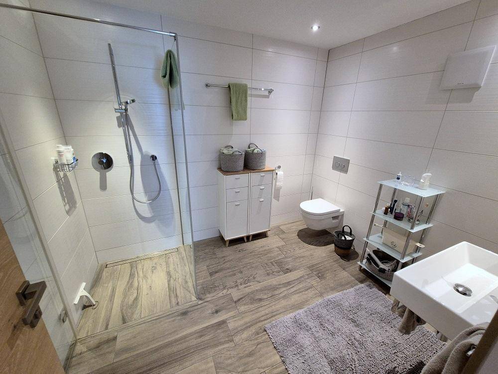 Modernes Badezimmer mit begehbarer Dusche, Wand-WC und Einzelwaschbecken.