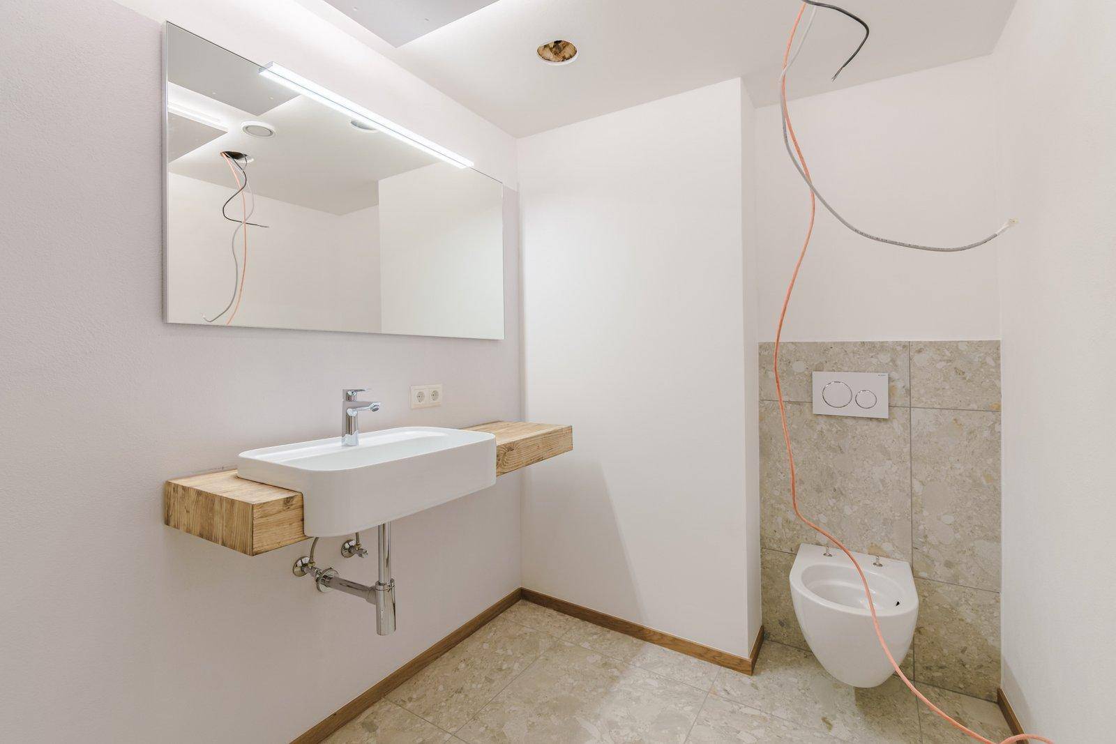 Badezimmer mit modernem Waschtisch, Wand-WC und Fliesen, noch in Fertigstellung.