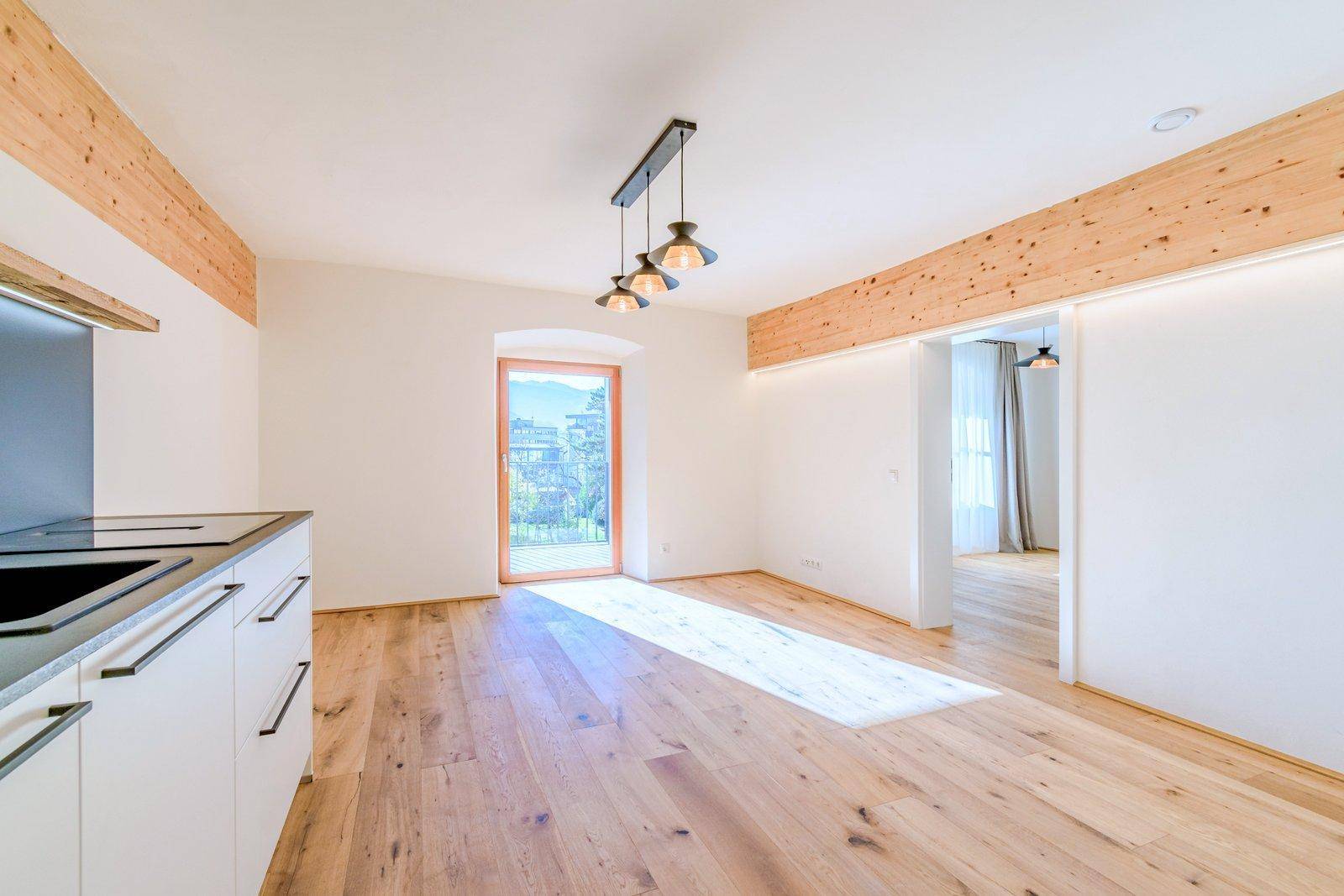 Lichtdurchfluteter Küchenbereich mit Holzboden und Zugang zu einem französischen Balkon.