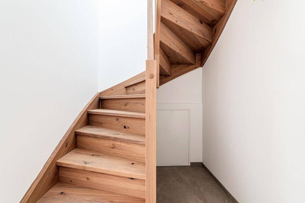 Elegante Holztreppe mit offenen Stufen, die verschiedene Ebenen des Hauses verbindet.