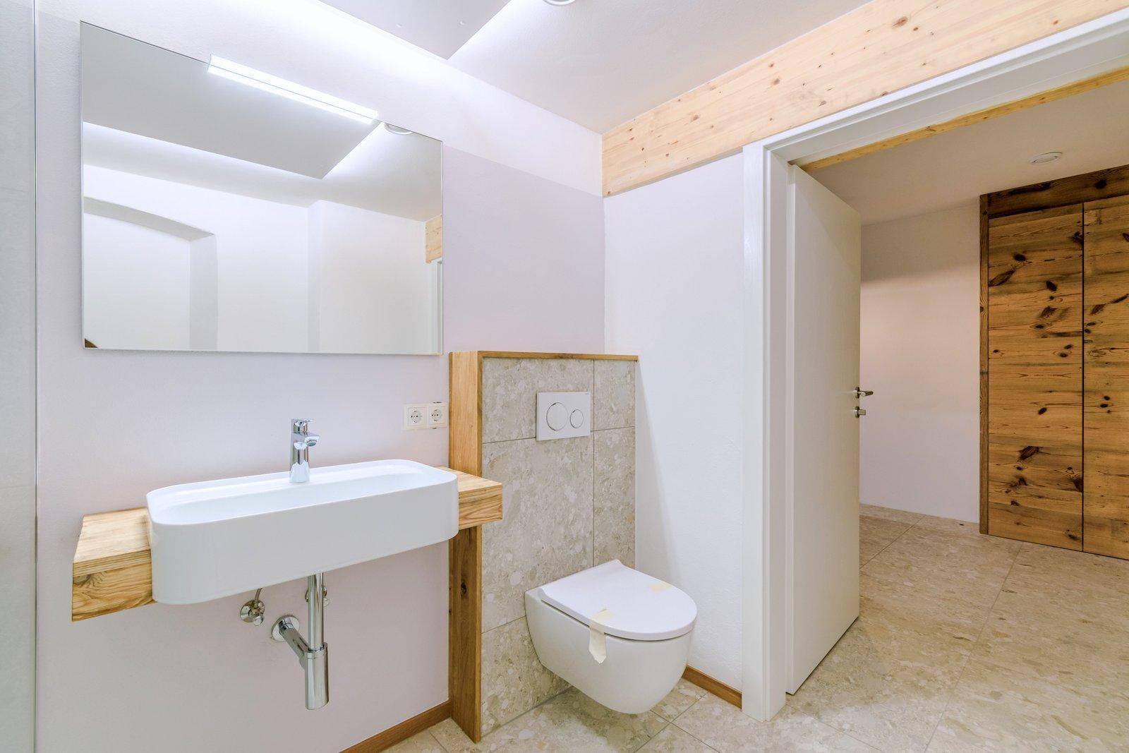 Stilvolles Badezimmer mit wandhängendem WC, modernem Waschbecken und großem Spiegel.