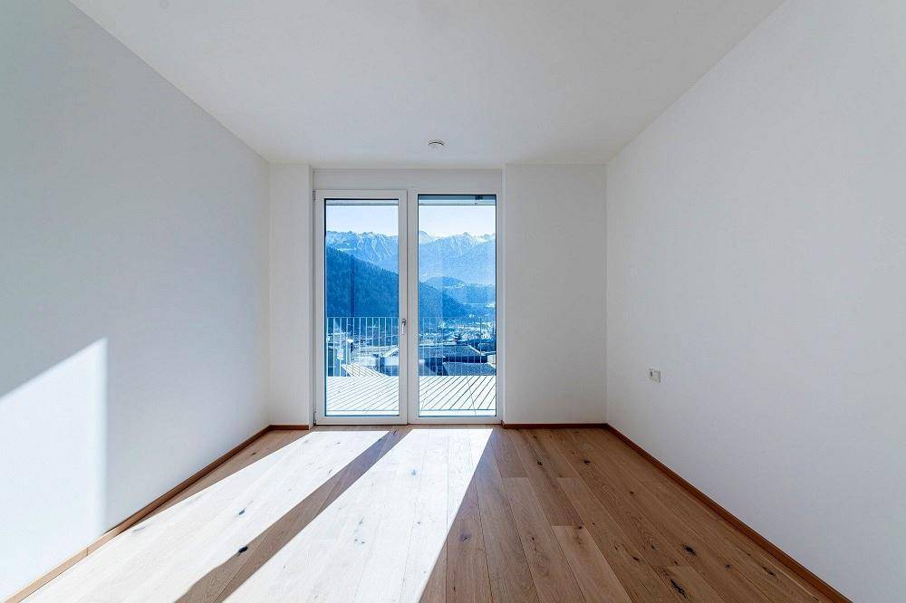 Helles Schlafzimmer mit Eichenparkett und Balkonzugang, bietet einen weiten Bergblick.