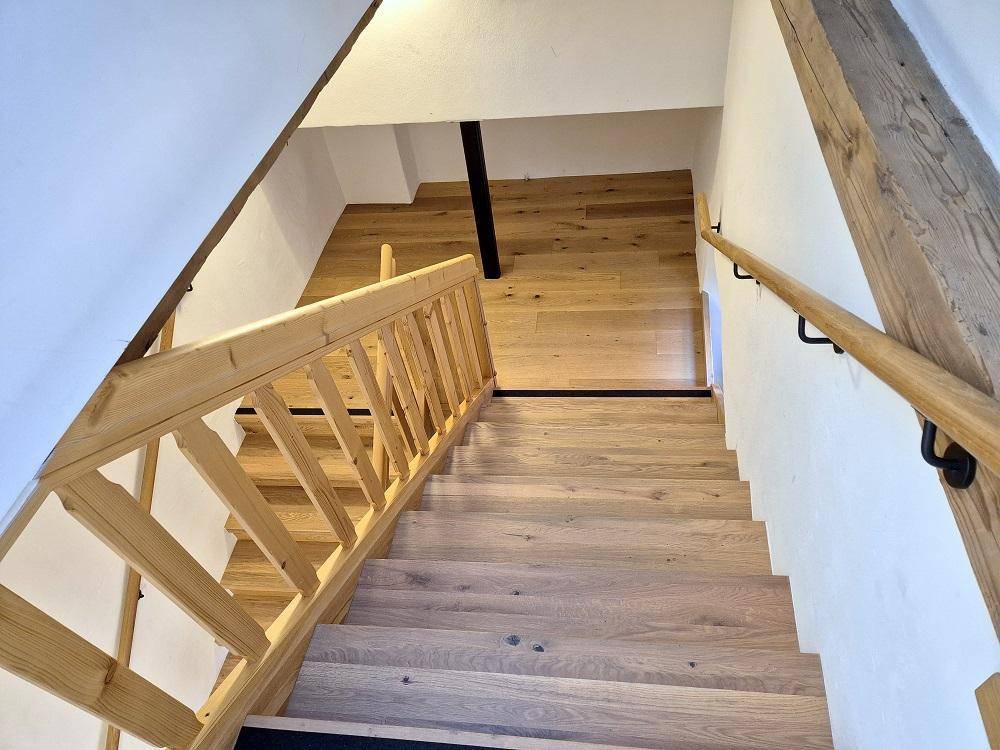 Elegante Holztreppe mit passendem Holzgeländer, die die verschiedenen Ebenen des Hauses verbindet.