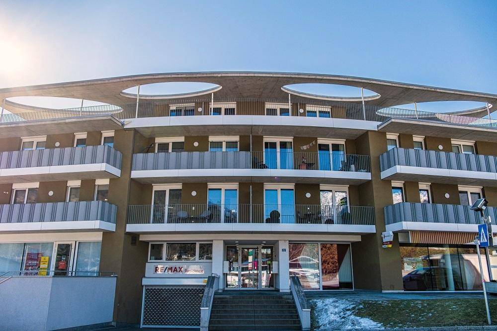 Eingangsbereich des modernen Gebäudes mit Treppe und großen Fenstern.