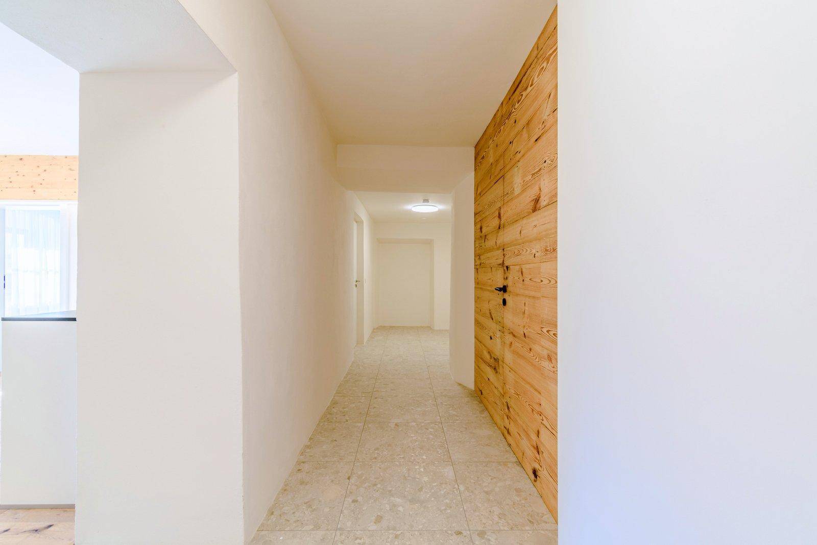 Heller Flur mit modernen Fliesen und einer Holzwand, die einen warmen Akzent setzt.