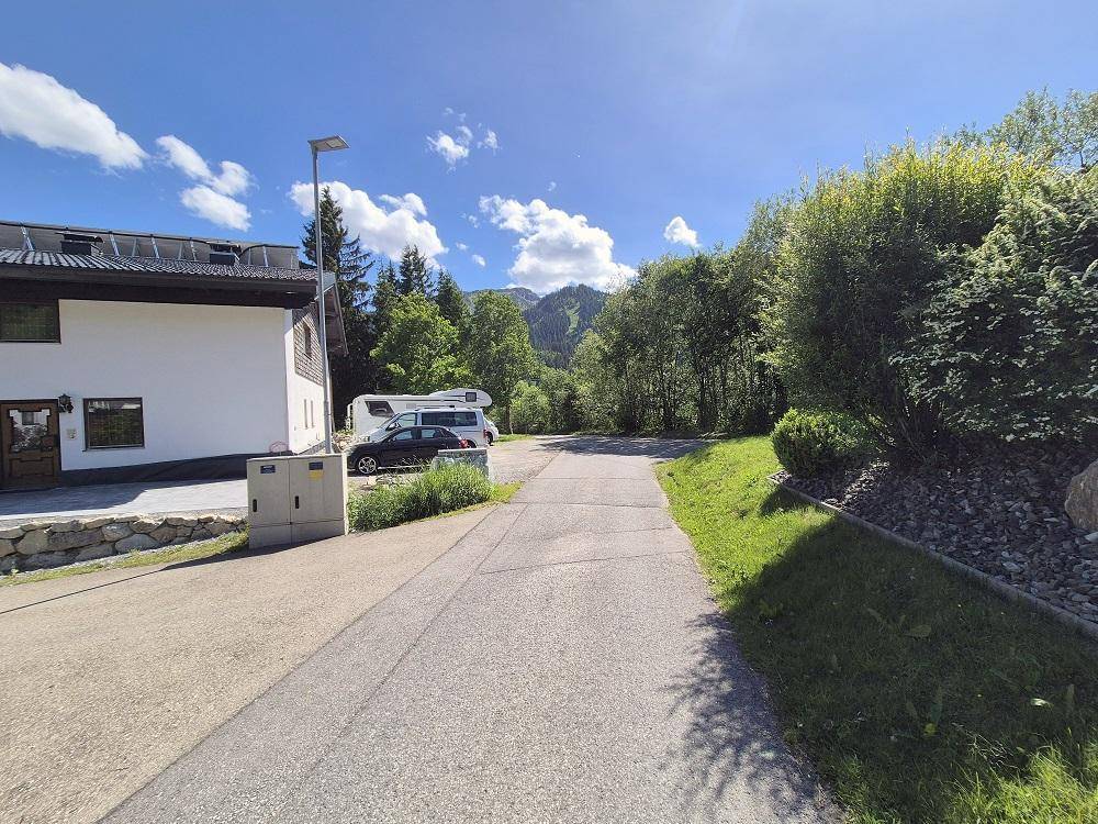 Wohngegend mit Häusern, geparkten Fahrzeugen und bewaldeten Bergen im Hintergrund.