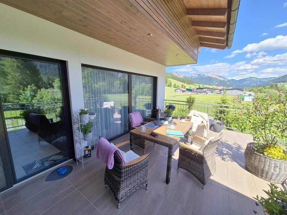 Große überdachte Terrasse mit Sitzgelegenheiten und Panoramablick auf die umliegende Berglandschaft.
