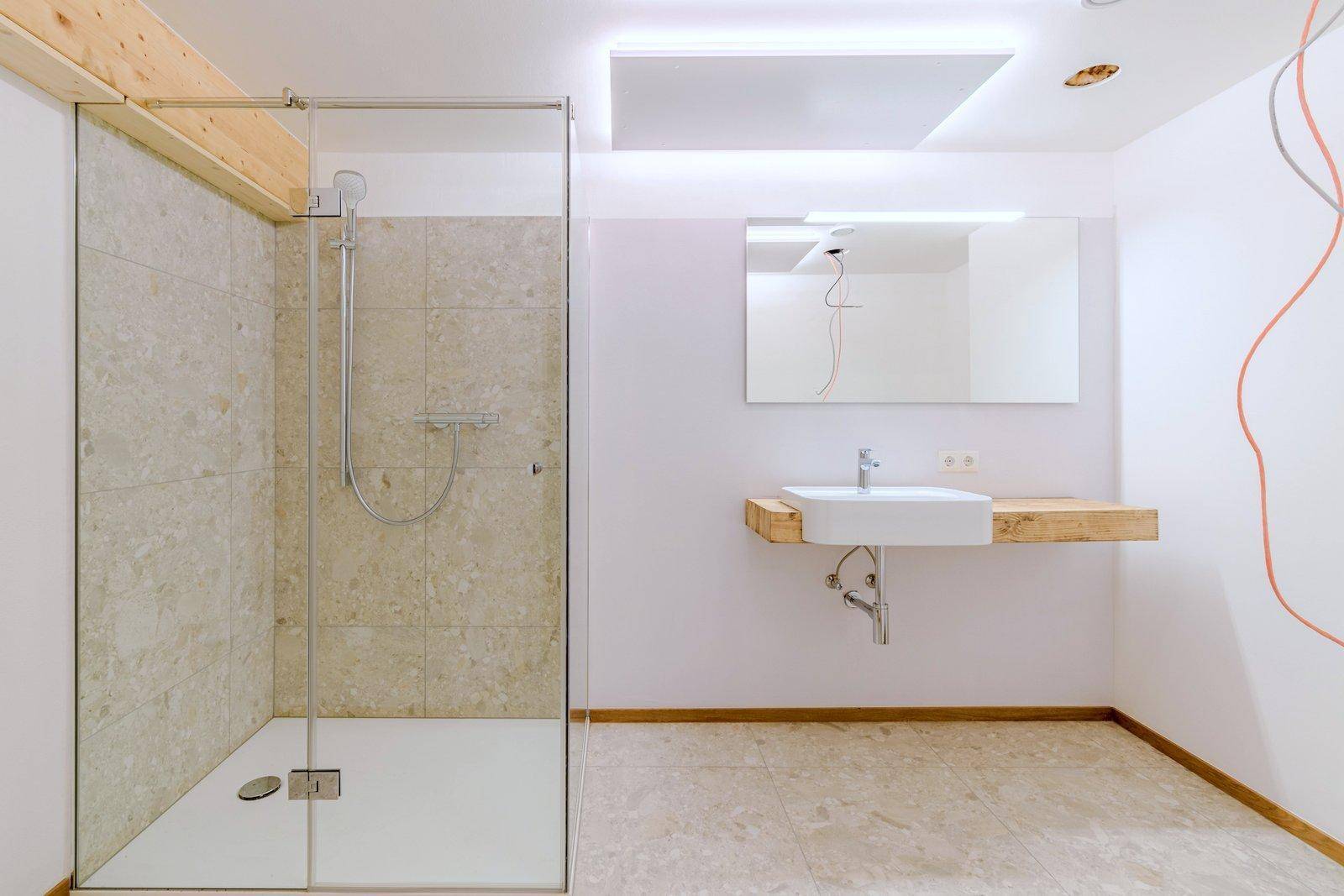 Helles Badezimmer mit großer Dusche, modernem Waschtisch und Fliesenboden.