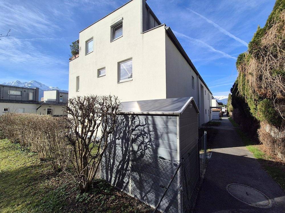 Seitenansicht des Gebäudes mit einem Gartenschuppen und gepflegter Hecke.