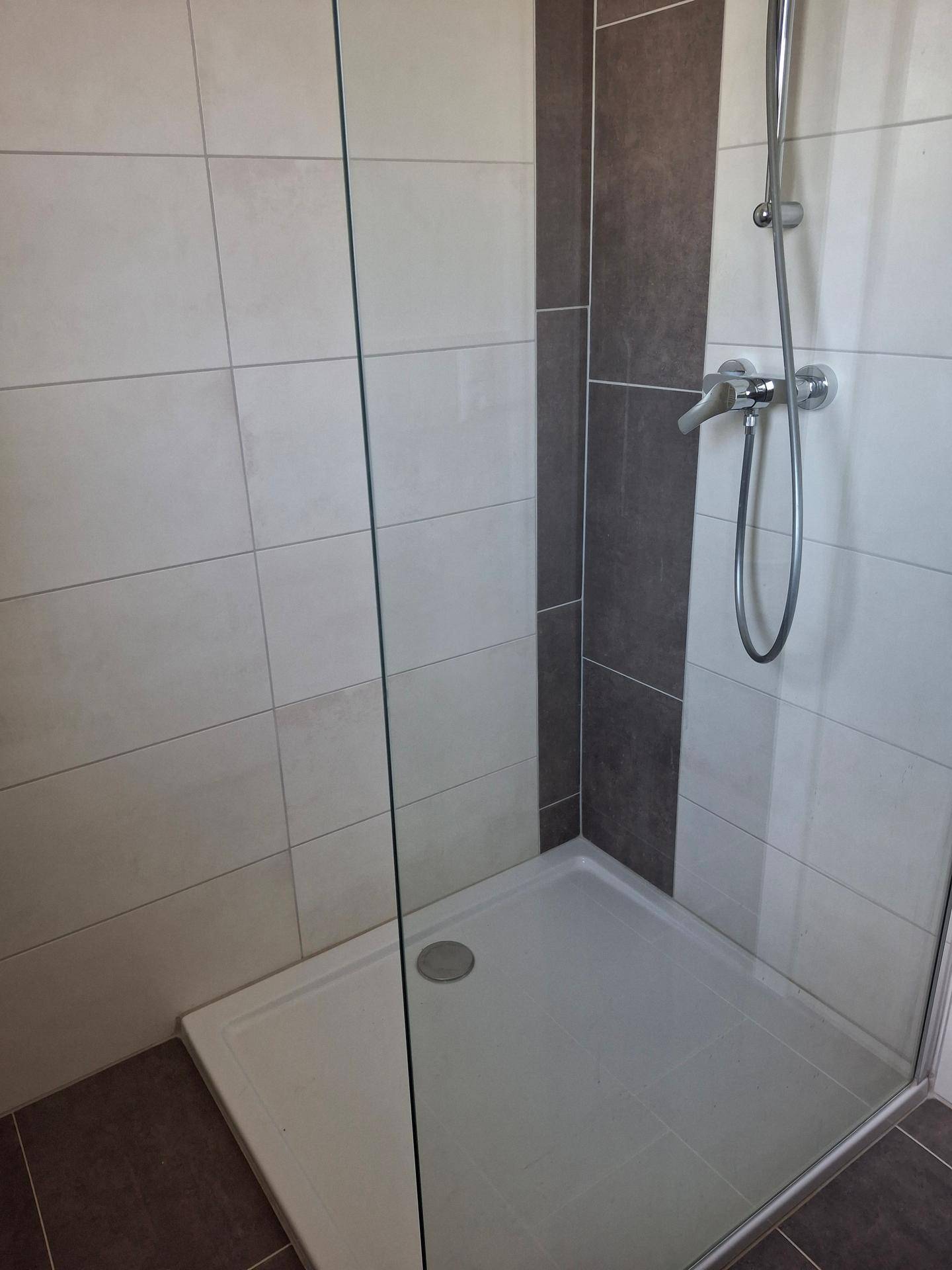 Detaillierte Ansicht der Duschkabine mit Glasabtrennung und modernen Fliesen im Badezimmer.