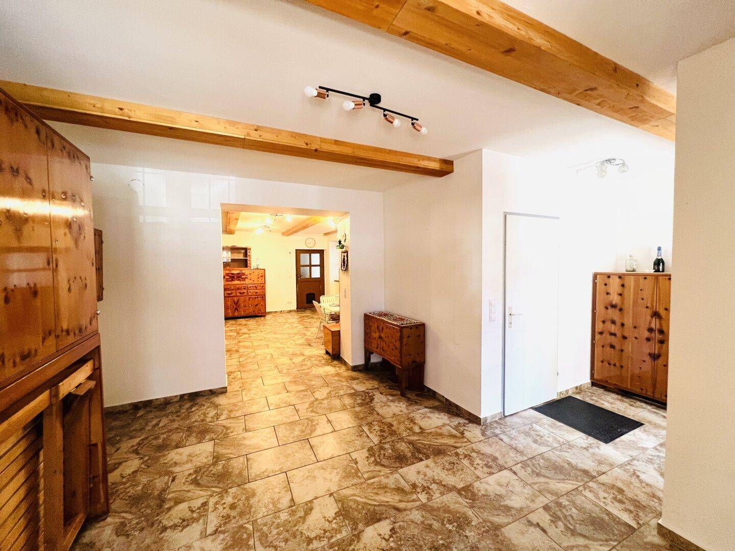 Geräumiger Flur mit rustikalen Holzmöbeln, Fliesenboden und sichtbaren Deckenbalken.