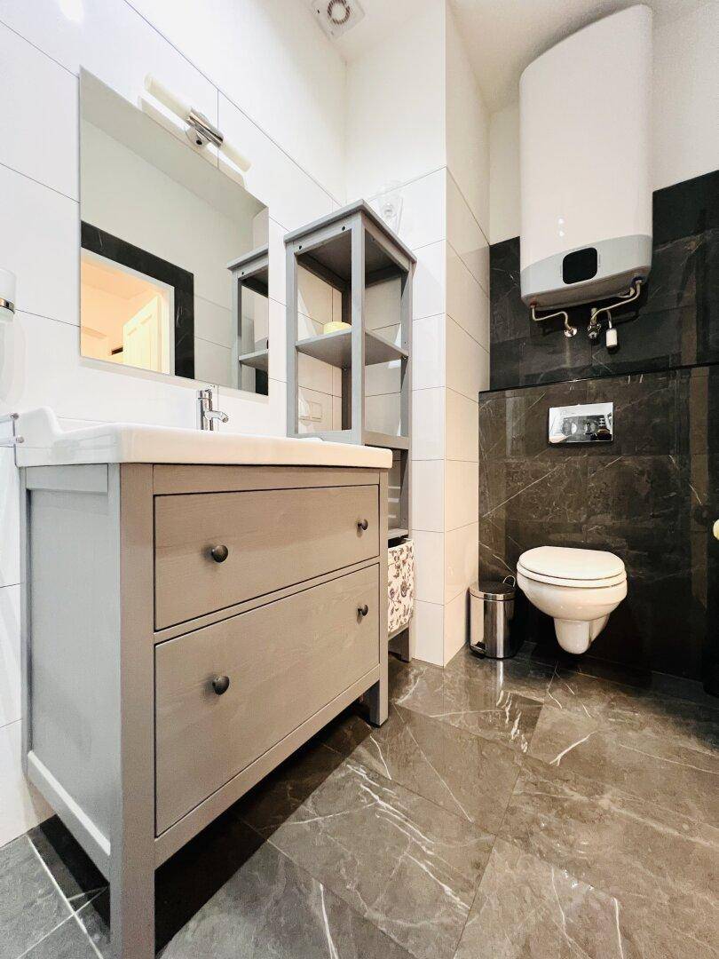 Modernes Badezimmer mit Waschtisch, Toilette und dunklem Fliesenboden.