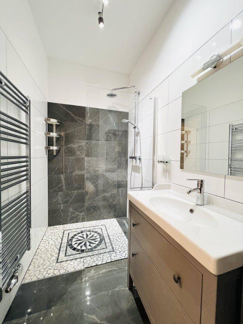 Modernes Badezimmer mit begehbarer Dusche, beheiztem Handtuchhalter und stilvollem Fliesenmuster.