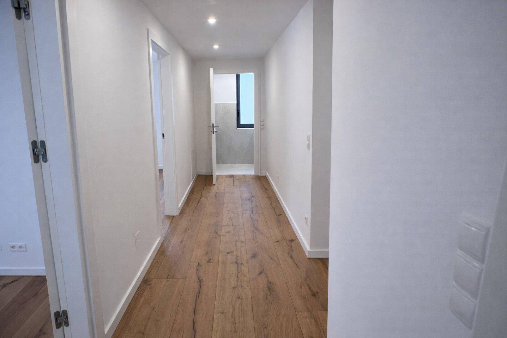 Heller Flur mit Holzboden und integrierter Deckenbeleuchtung.