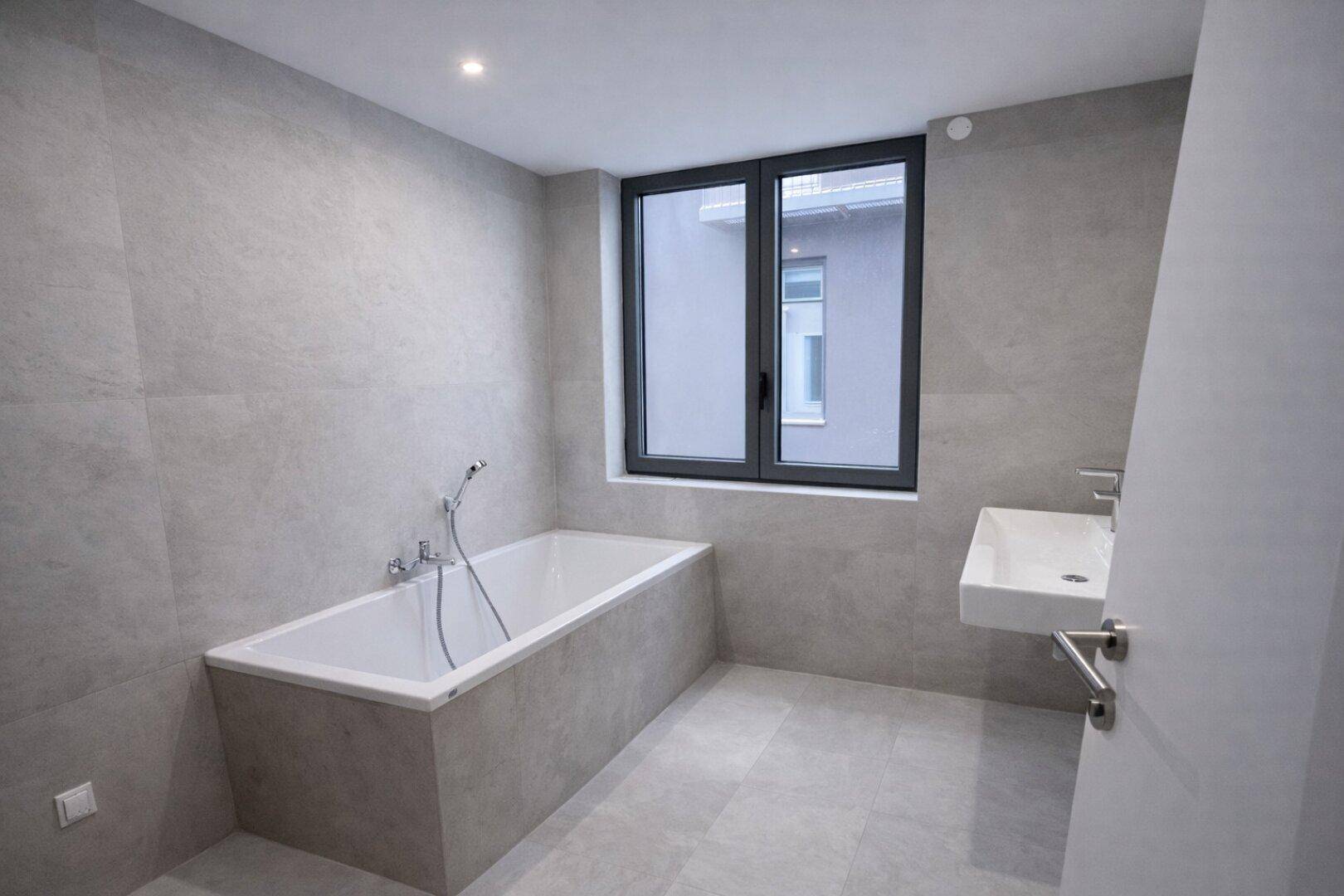 Modernes Badezimmer mit Badewanne, Einzelwaschbecken und Fenster.