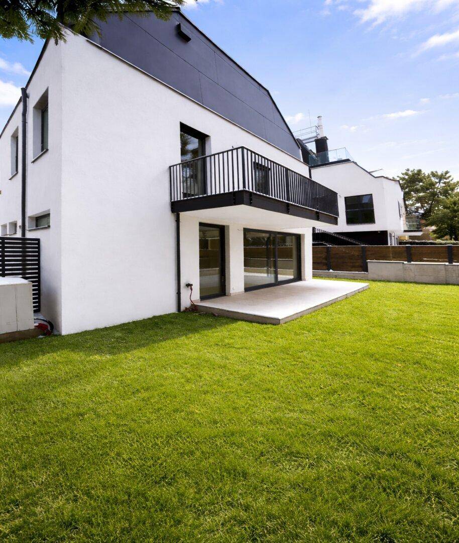 Modernes Haus mit weißer Fassade, großem Garten und sonniger Terrasse.