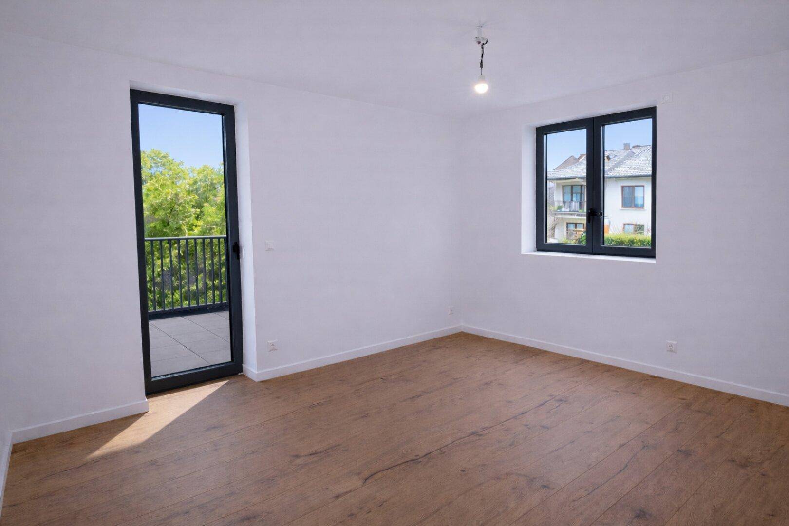 Helles Schlafzimmer mit Holzboden und direktem Zugang zum Balkon.
