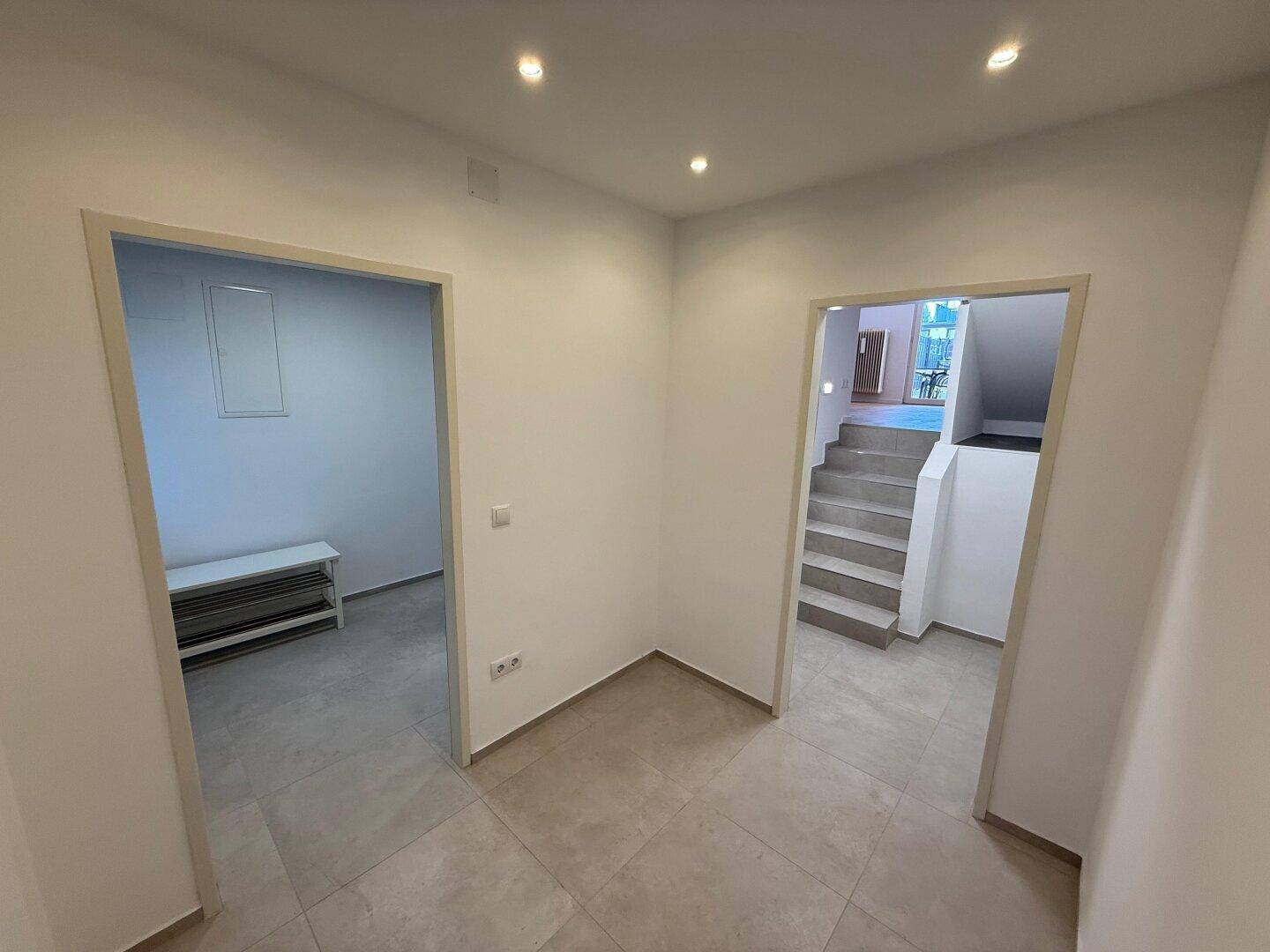 Heller Flurbereich mit Fliesenboden und Zugang zu verschiedenen Räumen sowie einer Treppe.