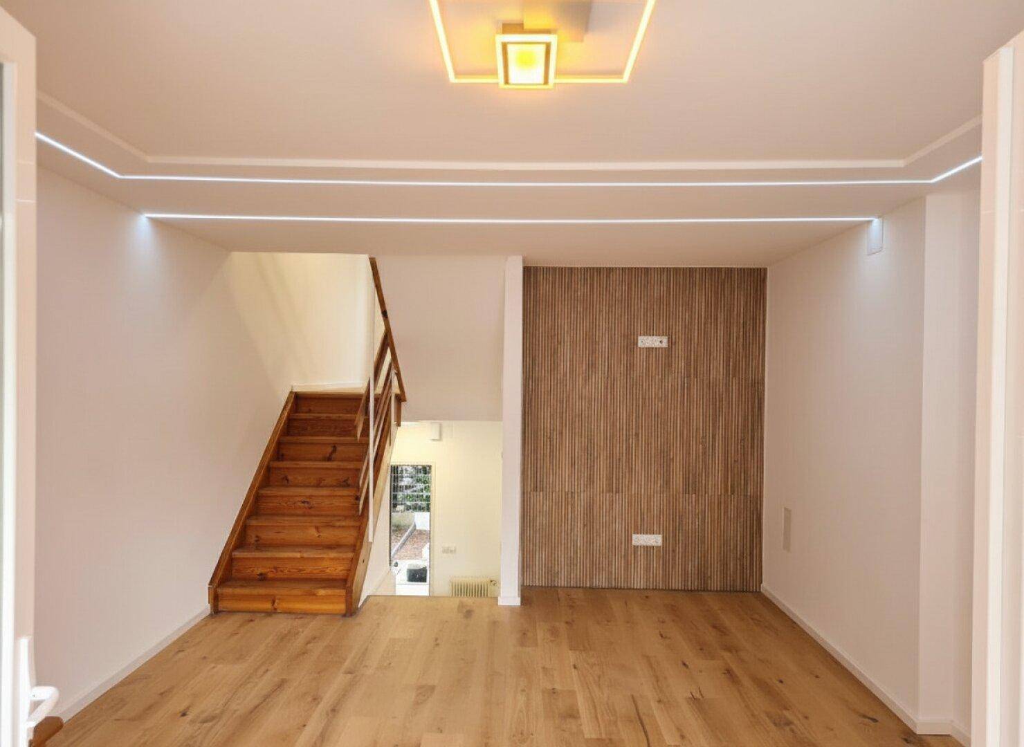 Heller Wohnbereich mit modernem Deckenlicht, Holzfußboden und einer stilvollen Holzlamellenwand.