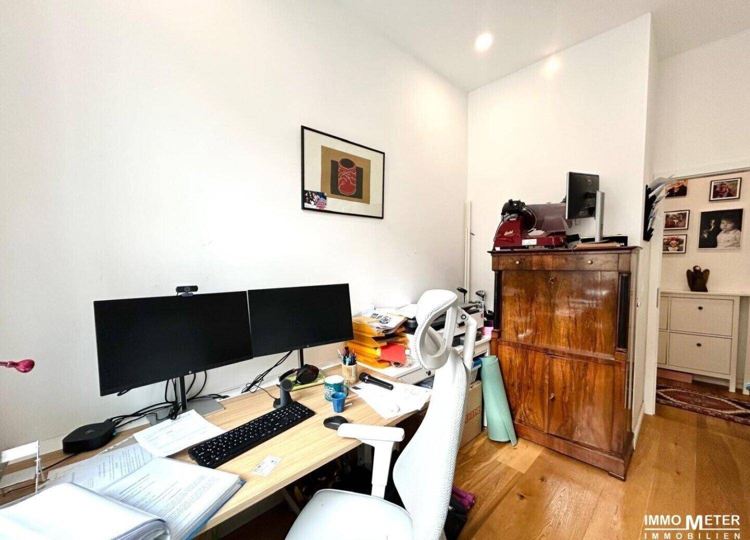 Funktionales Arbeitszimmer mit Holzboden, großem Schreibtisch und ausreichend Stauraum.