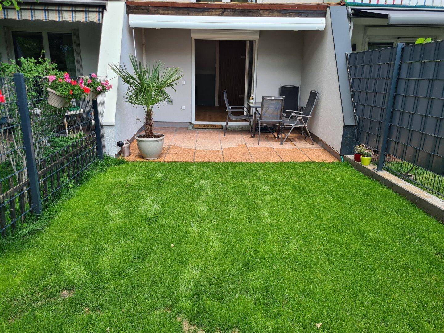 Gepflegter Gartenbereich mit kleiner Terrasse und Sitzgelegenheiten, ideal für entspannte Stunden im Freien.