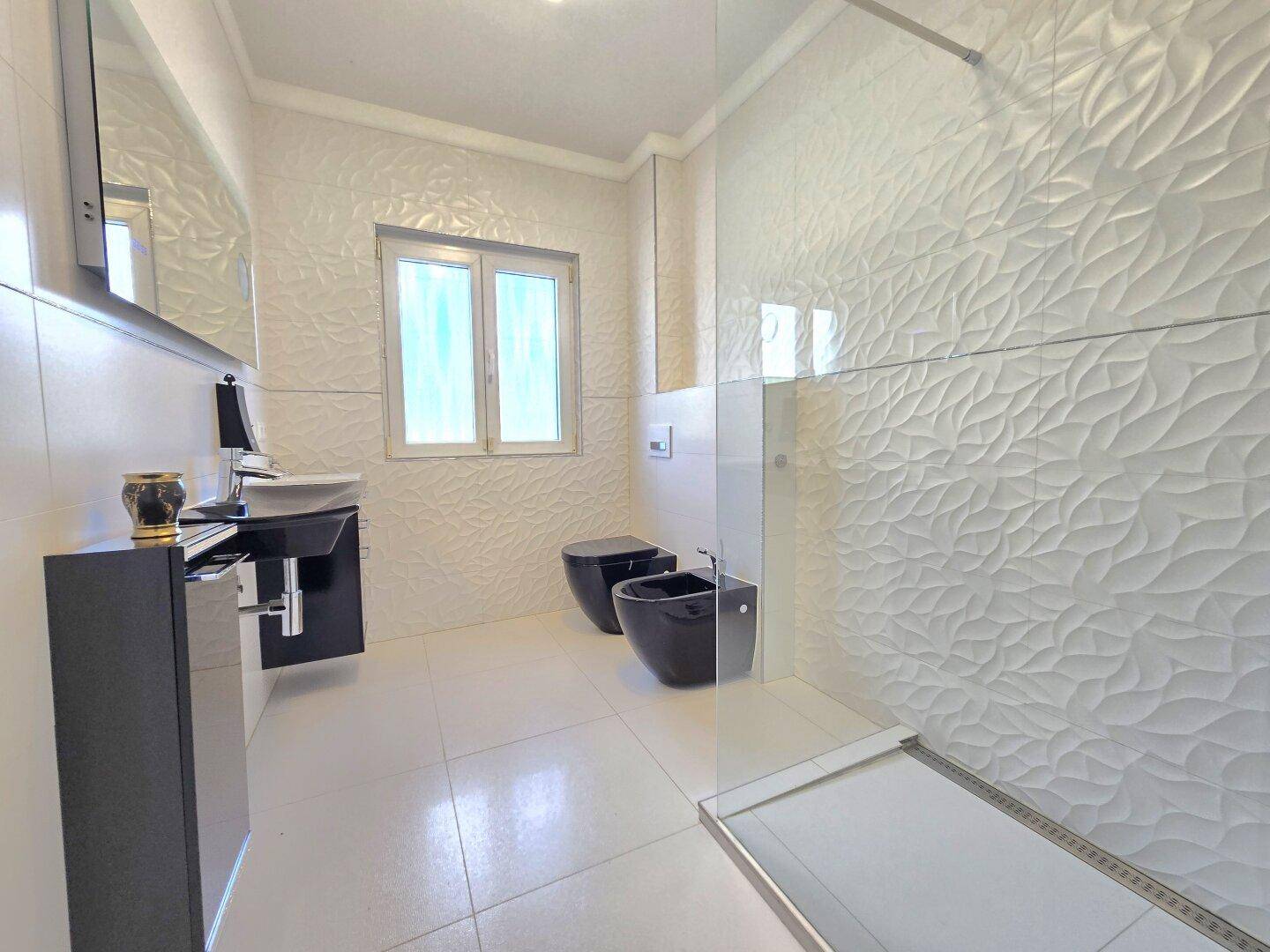 Helles modernes Badezimmer mit begehbarer Dusche, schwarzen Sanitärobjekten und Fenster.