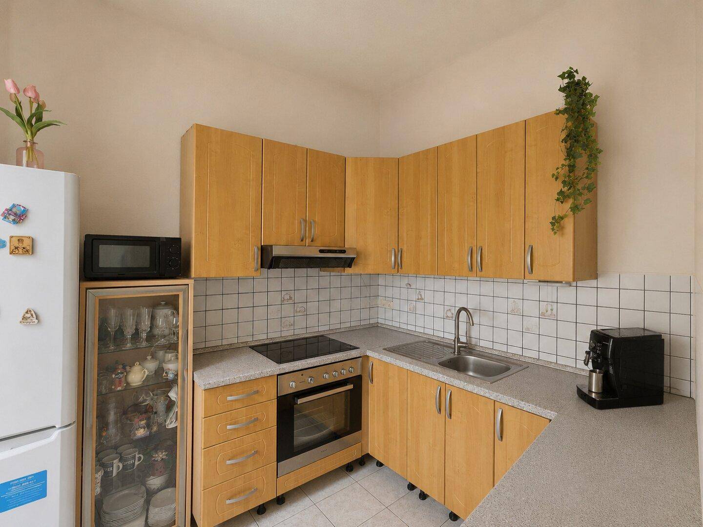 Funktionale Küche mit hellen Holzschränken, Fliesenrückwand und integrierten Geräten.