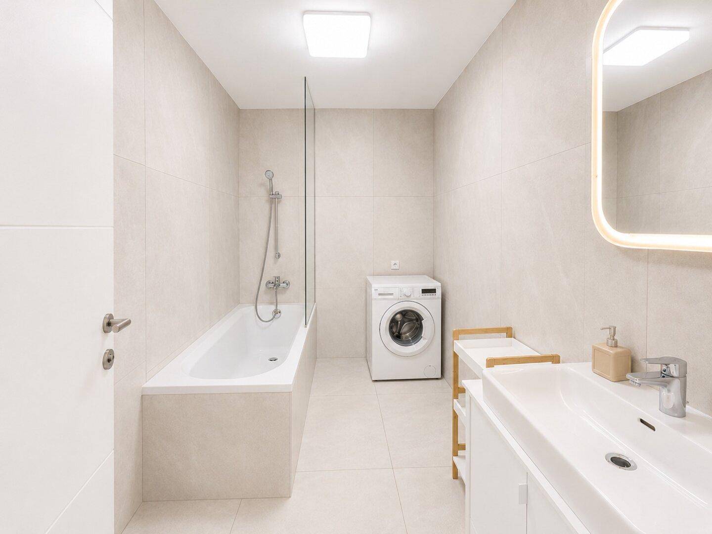 Modernes Badezimmer mit Badewanne, Waschbecken und Waschmaschine in hellen, neutralen Tönen.