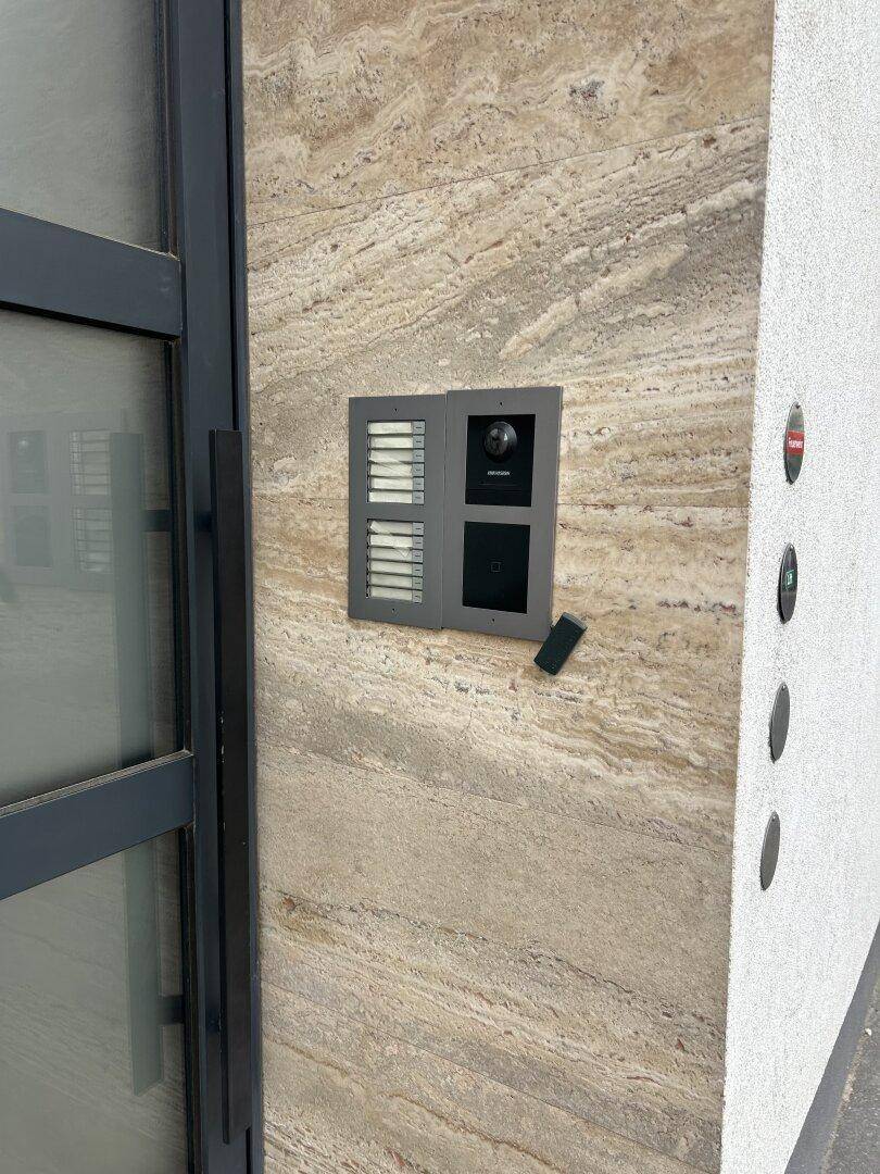 Moderne Gegensprechanlage und Klingelpanel an einer Außenwand mit Natursteinverkleidung.