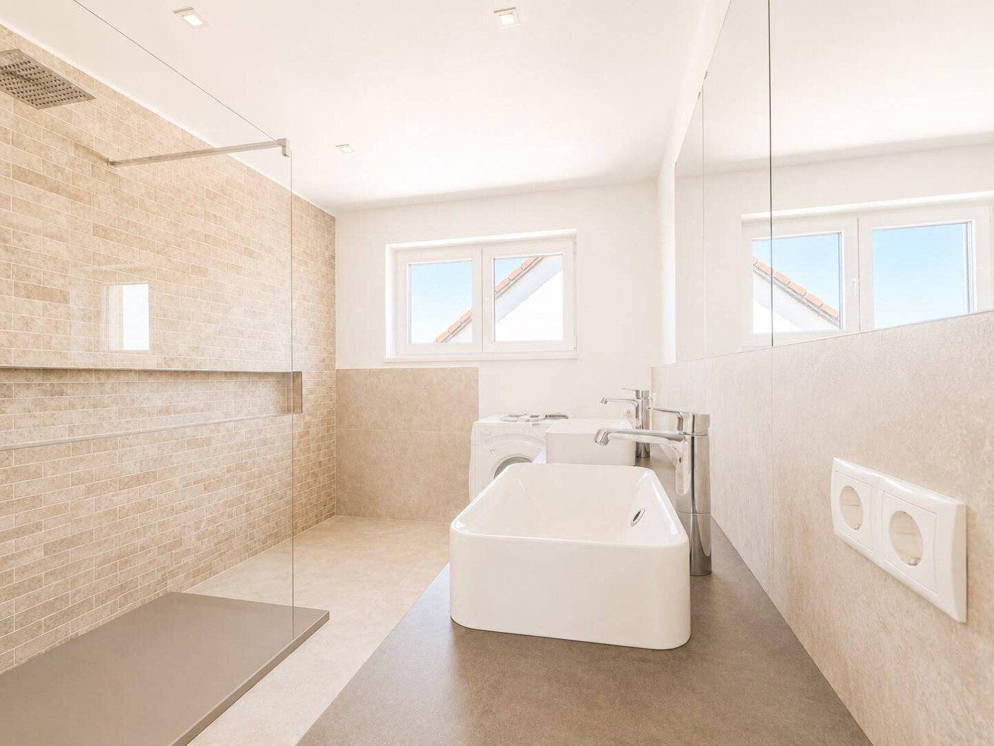 Modernes Badezimmer mit ebenerdiger Dusche, Einzelwaschbecken und Fenster, inklusive Waschmaschinenanschluss.