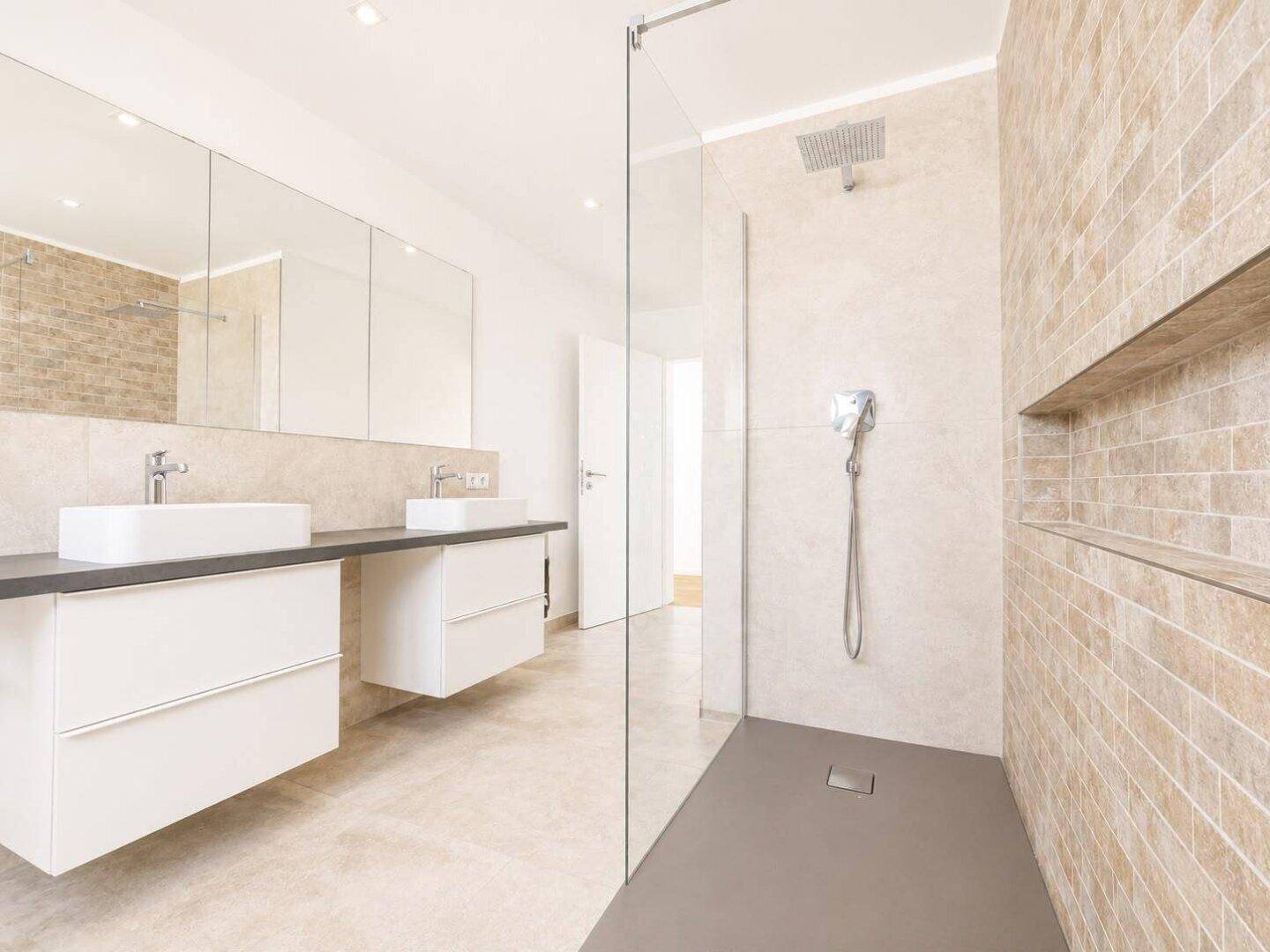 Modernes Badezimmer mit ebenerdiger Dusche, Doppelwaschbecken und großen Spiegeln.