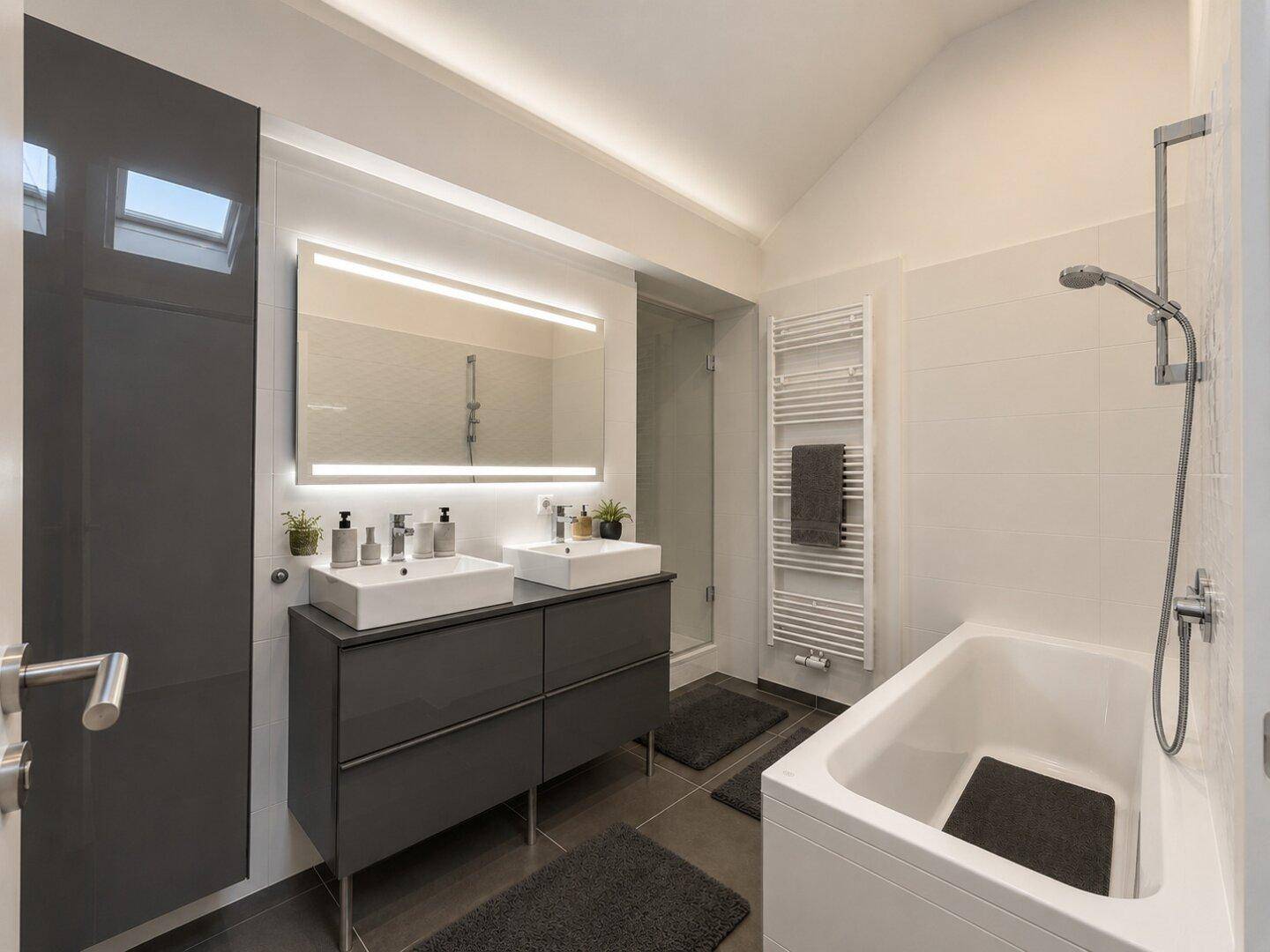 Modernes Badezimmer mit Doppelwaschbecken, Badewanne und beheiztem Handtuchhalter.