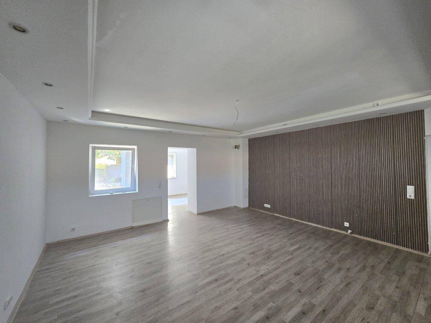 Heller Raum mit modernem Laminatboden und einer dekorativen Holzlamellenwand, die einen Akzent setzt.