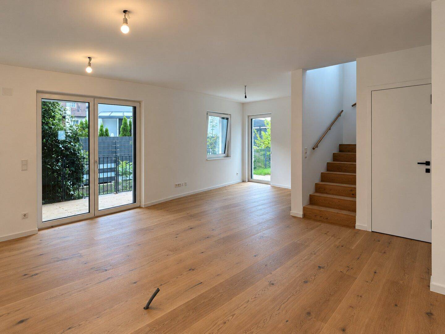 Geräumiger, heller Wohnbereich mit Eichenparkett, großen Fenstern und Zugang zur Terrasse.
