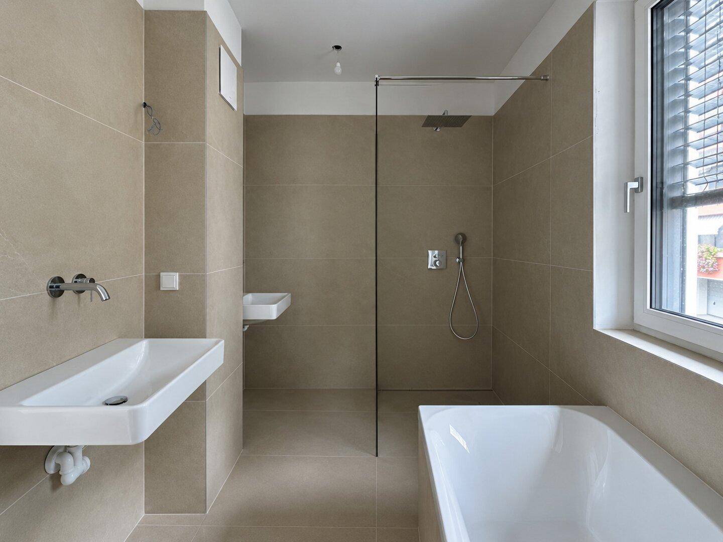 Modernes Badezimmer mit beigefarbenen Fliesen, Badewanne, ebenerdiger Dusche und Fenster.