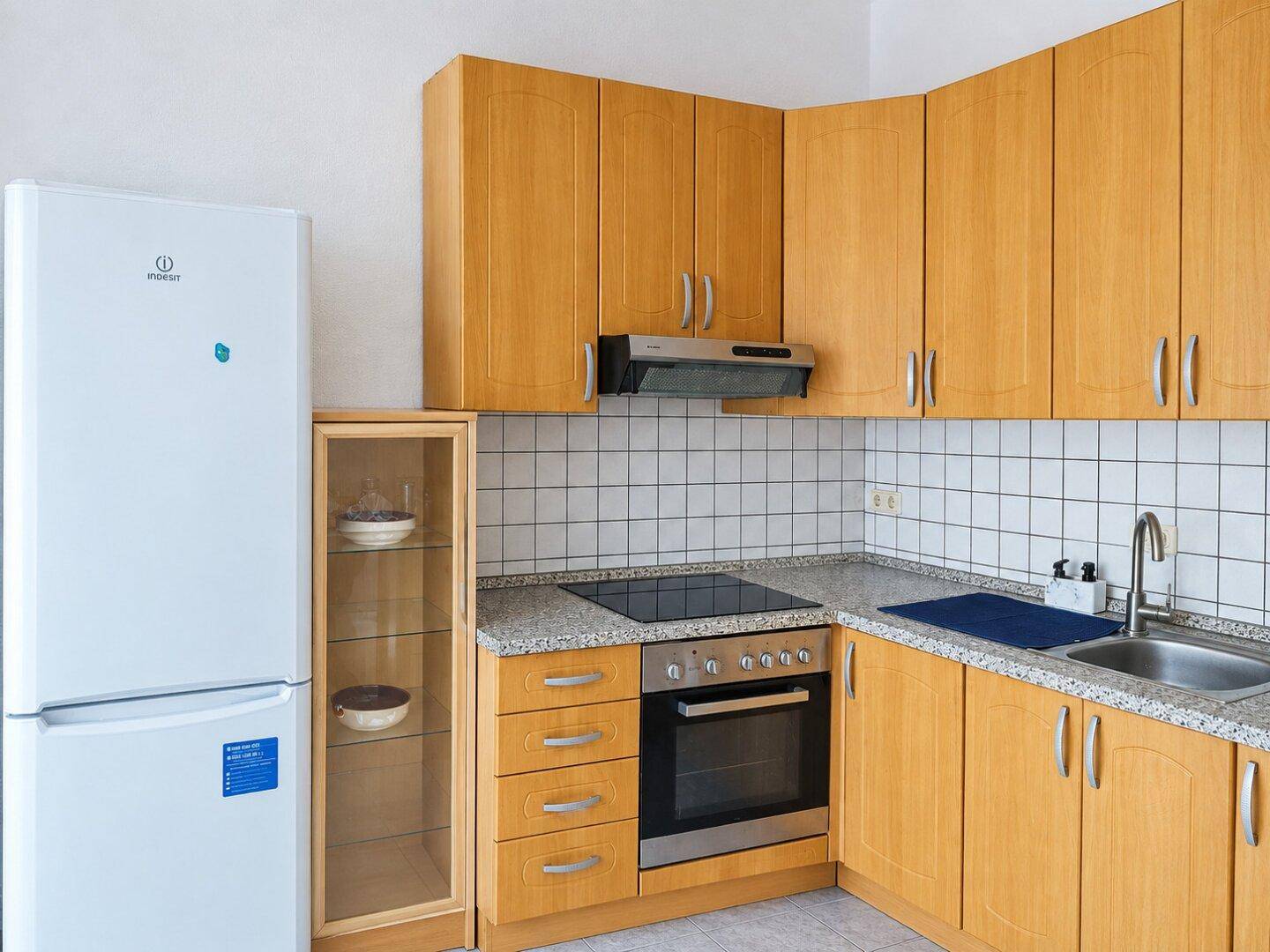 Funktionale Küche mit hellen Holzschränken, Granitarbeitsplatte und integrierten Geräten.