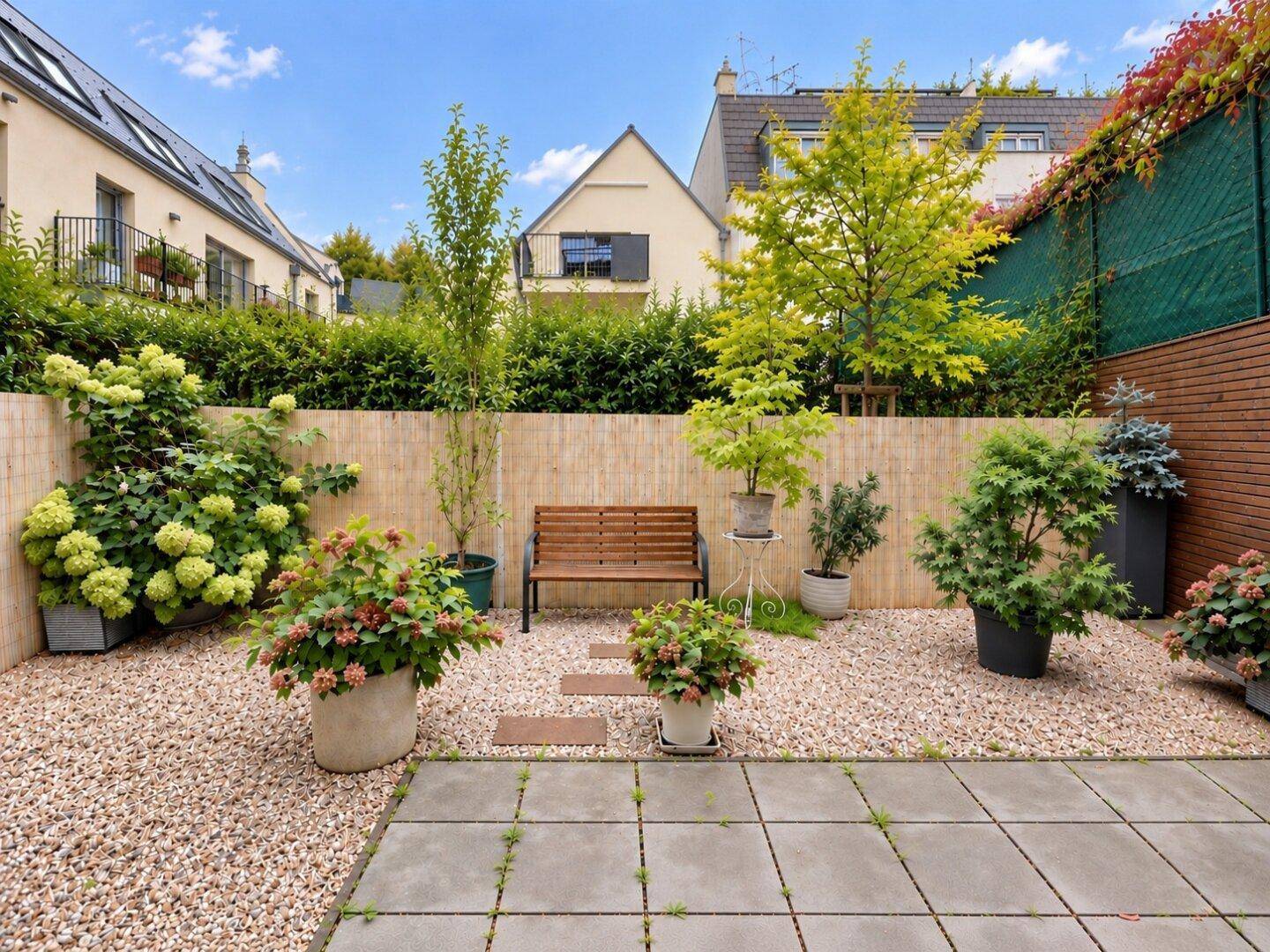 Gepflegter Gartenbereich mit Kies, Sitzbank und verschiedenen Pflanzen in Töpfen.