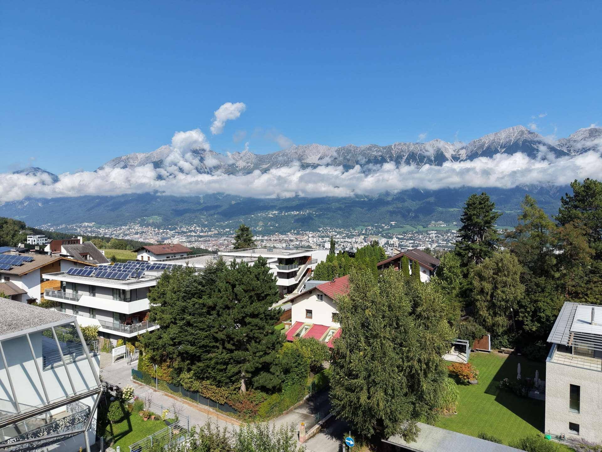 Panoramablick auf die Stadt und die majestätischen Berge unter einem klaren blauen Himmel.
