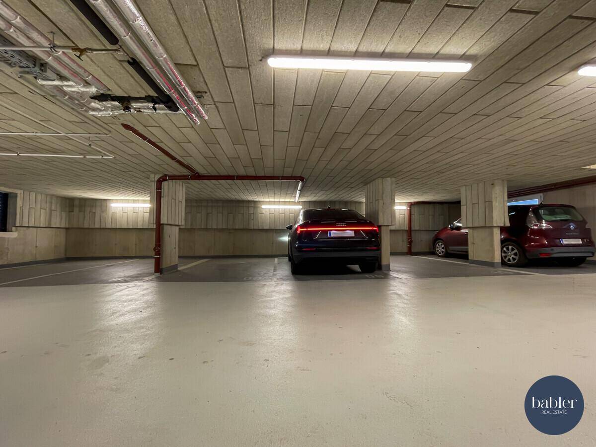 Saubere Tiefgarage mit Betonstruktur, modernen Fahrzeugen und funktionaler Beleuchtung.